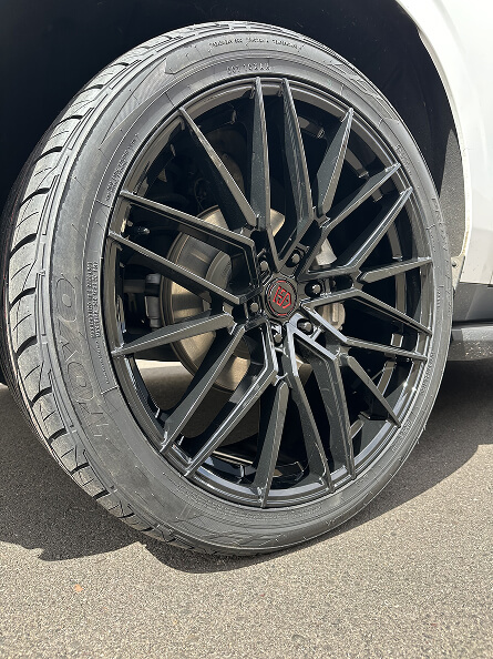 Black multi-spoke wheel and tire on a white SUV